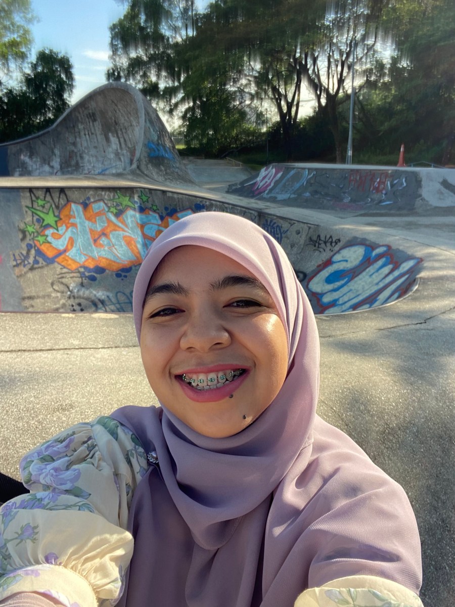 Smile hijabi woman in a soft purple hijab. She wears braces.